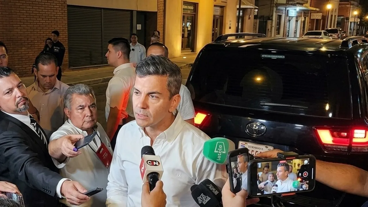 Santiago Peña habla ante micrófonos y periodistas de medios de comunicación en la vía pública de noche.