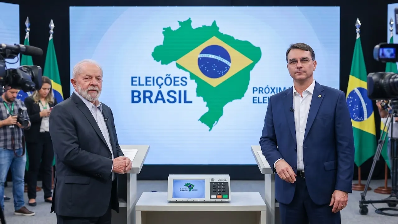 Flávio Bolsonaro y Lula da Silva de pie en un estudio televisivo frente a una urna electrónica de votación.