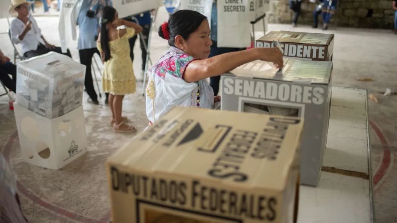 Una mujer con vestimenta tradicional deposita su voto en una urna de cartón durante una jornada electoral.