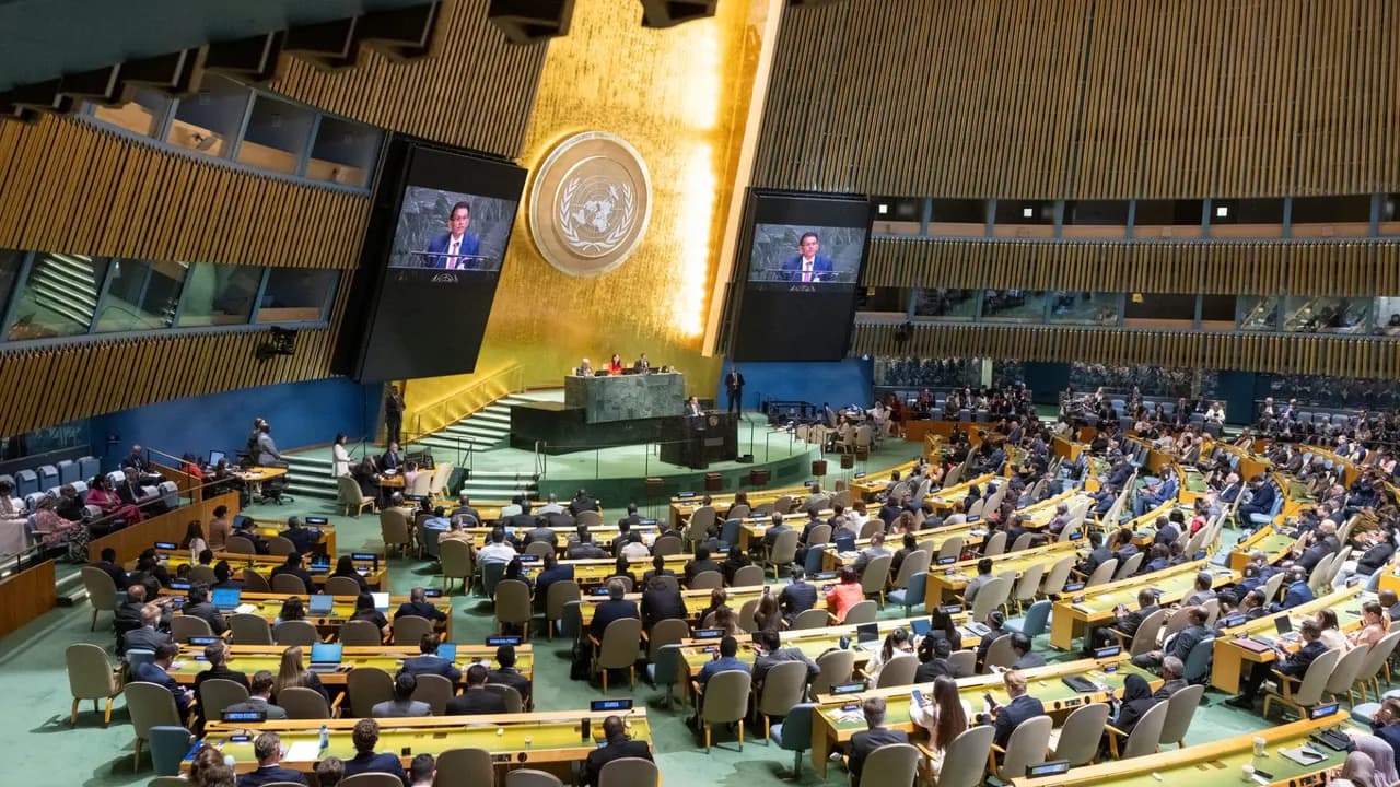 Delegados sentados en el plenario de la Asamblea General de la ONU durante un debate con pantallas gigantes.
