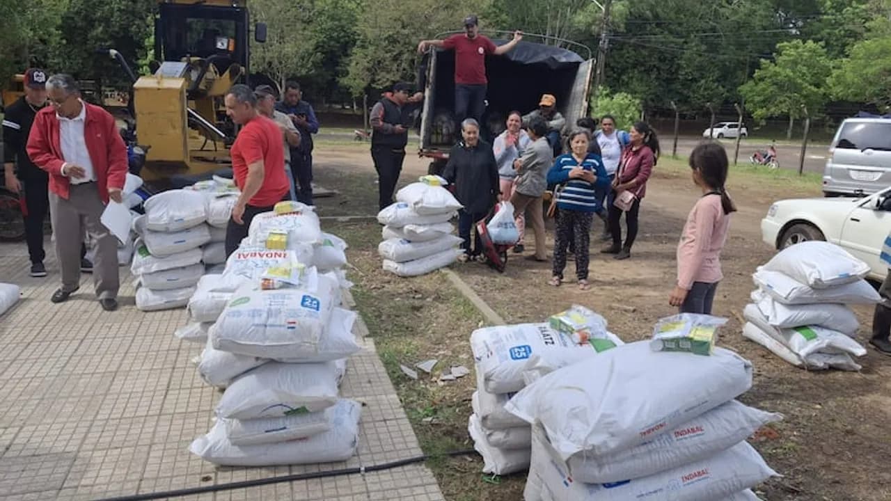 Pobladores y autoridades junto a bolsas apiladas de víveres e insumos cerca de un camión de carga.
