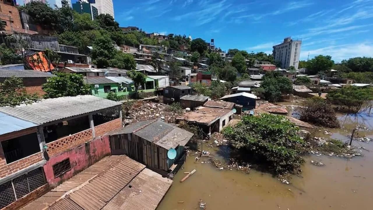 Viviendas anegadas por la crecida del río en una zona ribereña con construcciones precarias bajo cielo despejado