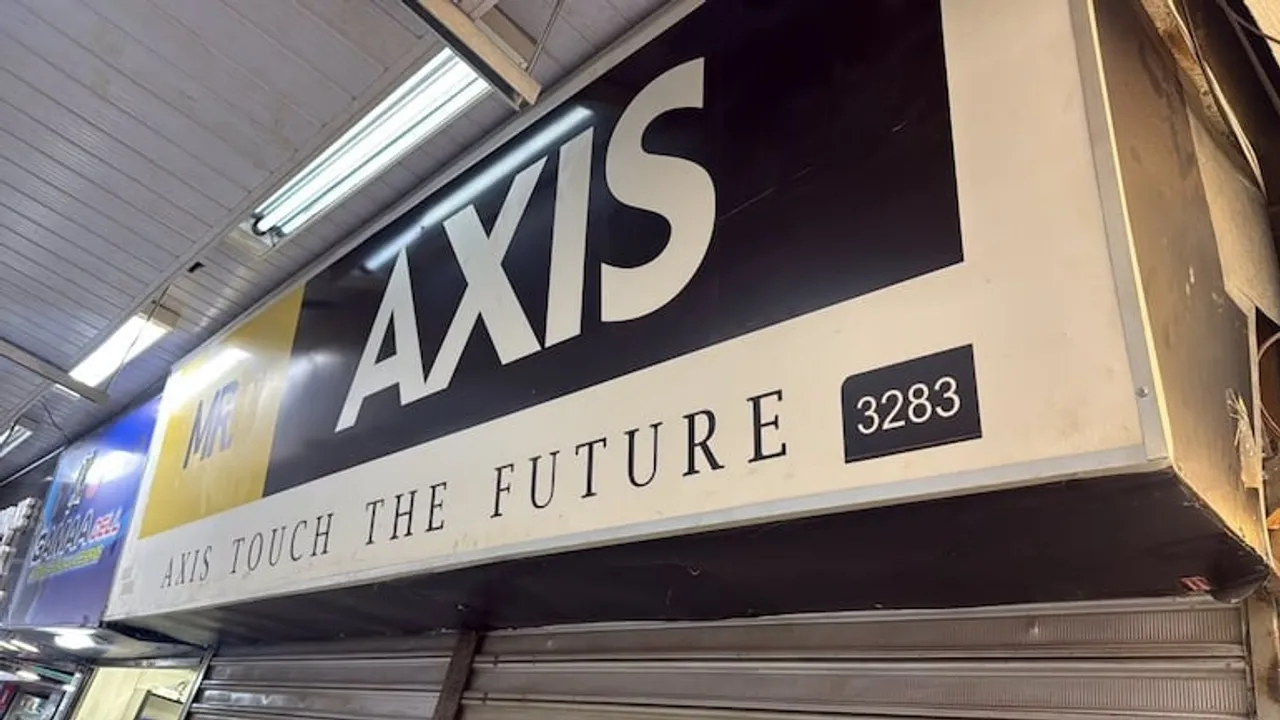 Cartel promocional del comercio Axis en una galería de Ciudad del Este con las cortinas metálicas cerradas.