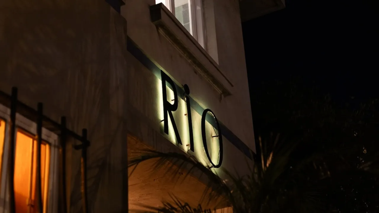 Letrero luminoso con la palabra RIO en la fachada exterior iluminada de un restaurante durante la noche