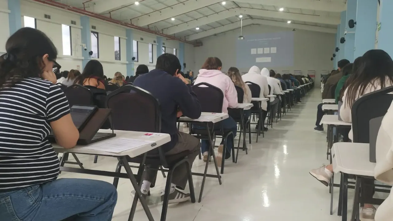 Postulantes sentados en pupitres individuales dentro de un amplio salón rinden una evaluación médica escrita.
