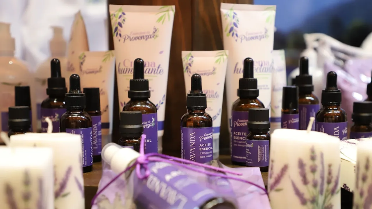 Frascos de vidrio con aceite esencial de lavanda, goteros y cremas humectantes exhibidos en un estante.