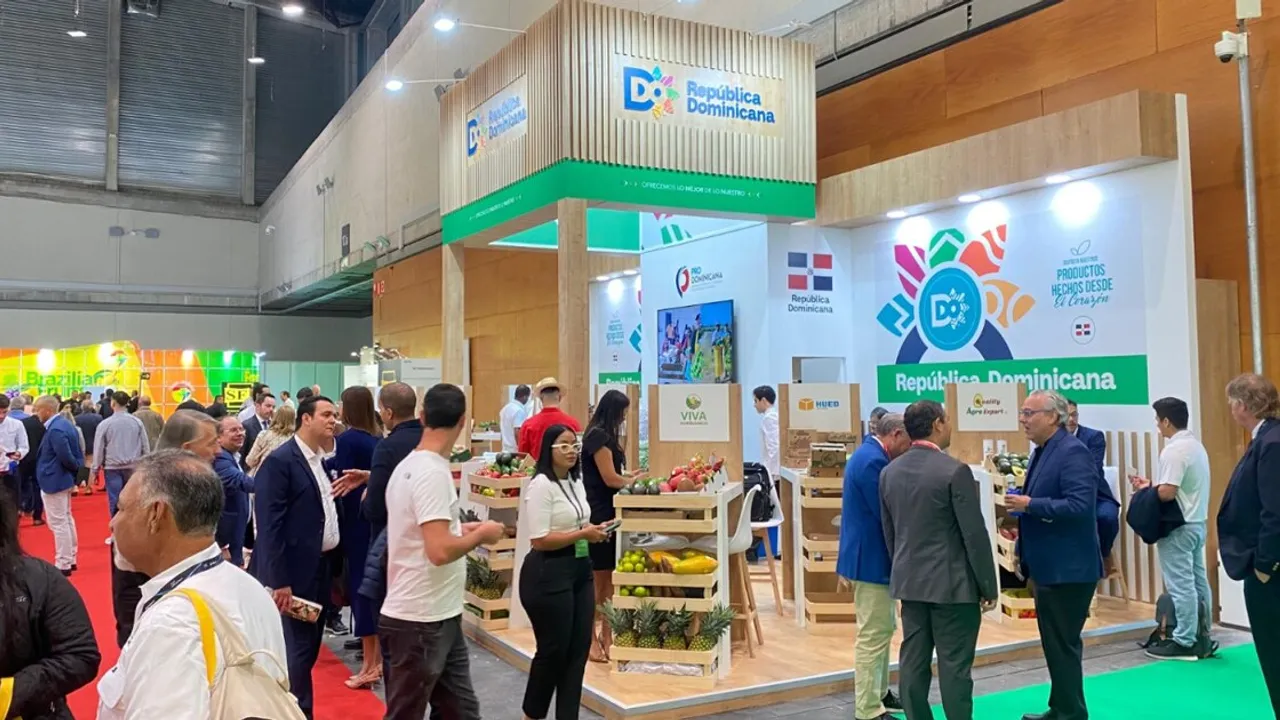 Stand de República Dominicana en una feria comercial con expositores de frutas tropicales y visitantes conversando.