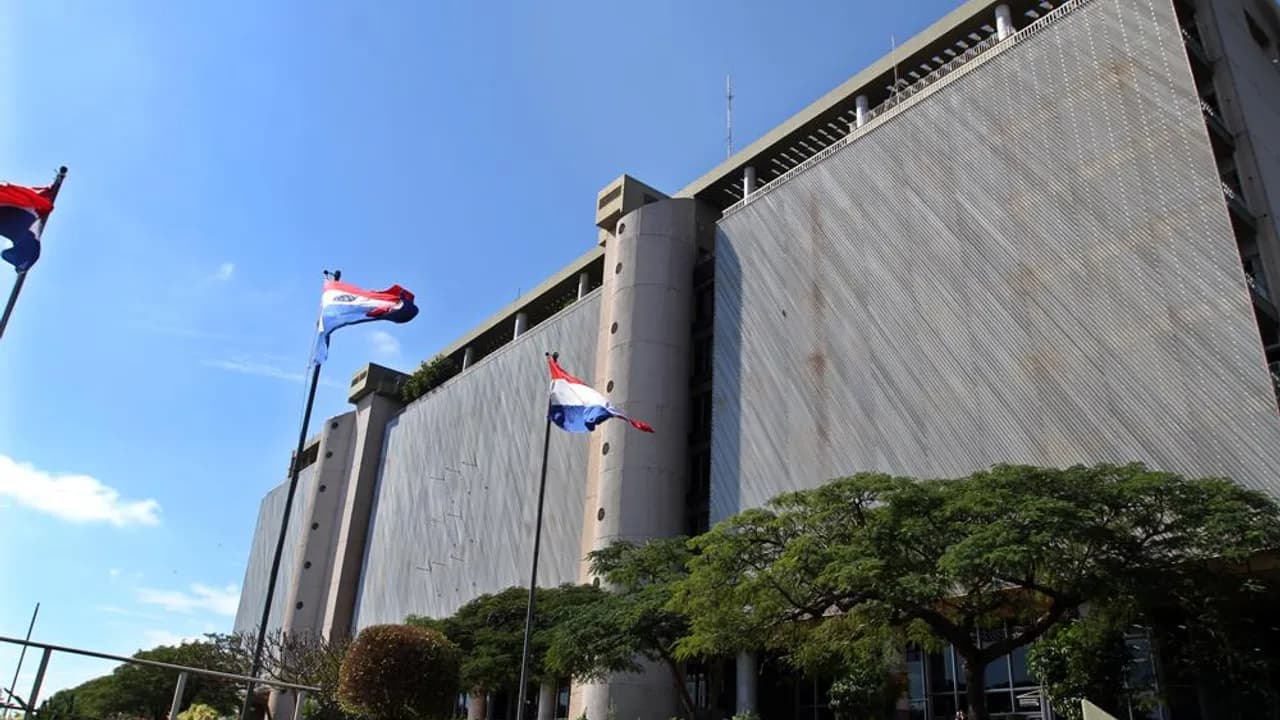 Fachada del edificio del Banco Central del Paraguay con banderas paraguayas flameando bajo el cielo azul.