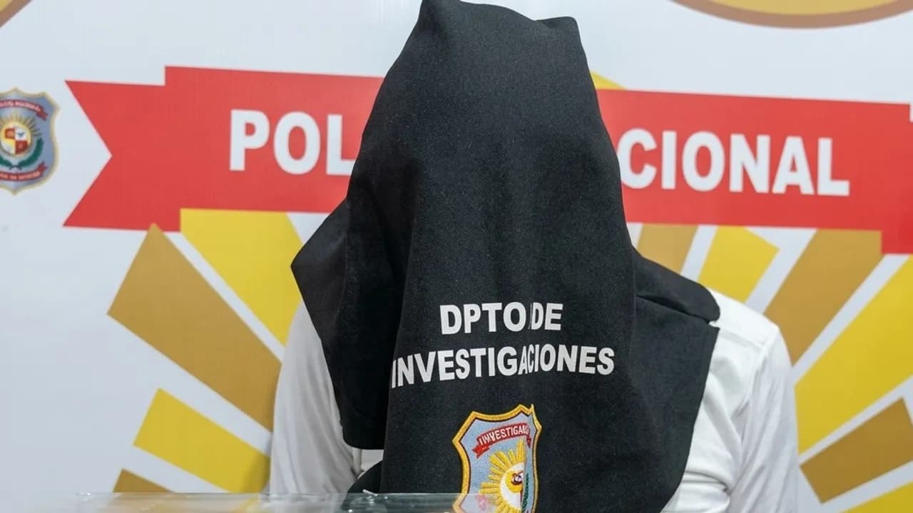 Persona detenida con la cabeza cubierta por una tela negra con la inscripción Dpto de Investigaciones.