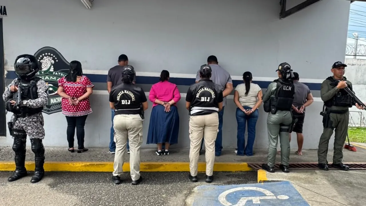 Varios detenidos de espaldas contra una pared con las manos esposadas y custodiados por policías uniformados.