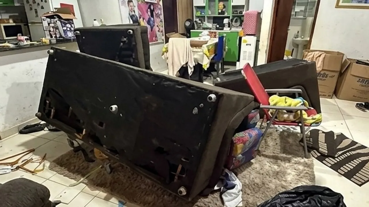 Sala de una vivienda con un sofá volcado y objetos desordenados tras un asalto violento.