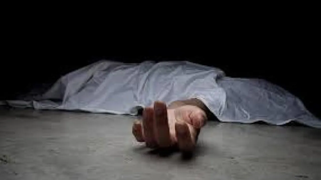Cuerpo cubierto con una sábana blanca tendido en el suelo con una mano extendida hacia el frente.