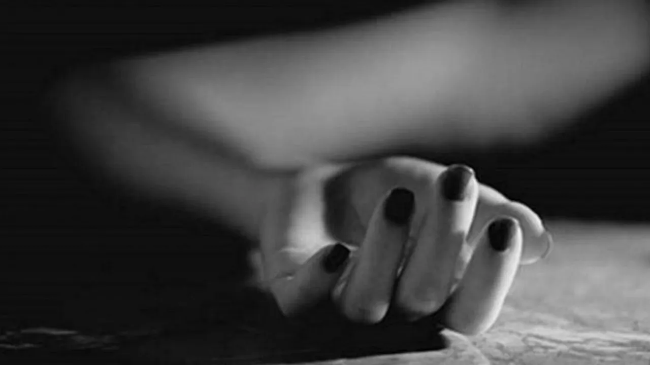 Primer plano en blanco y negro de la mano y el antebrazo inerte de una mujer descansando sobre una superficie.