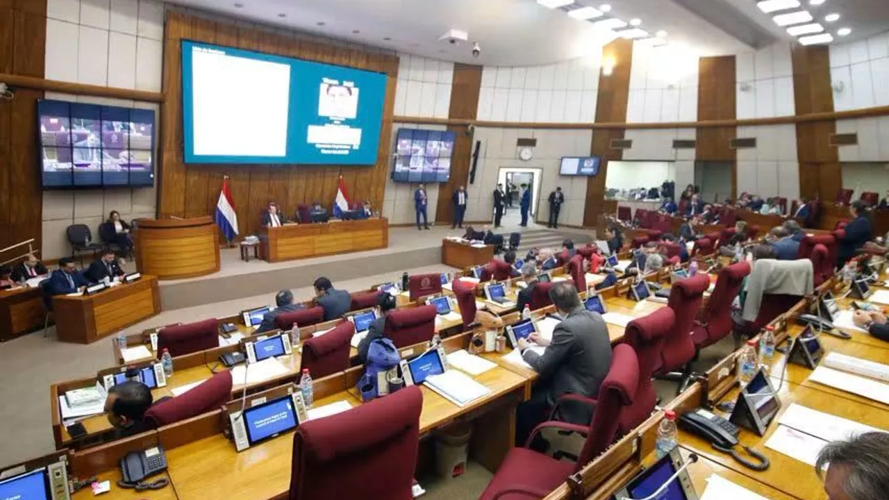 Sesión en la Cámara de Diputados de Paraguay con parlamentarios sentados en sus bancas y pantallas informativas.