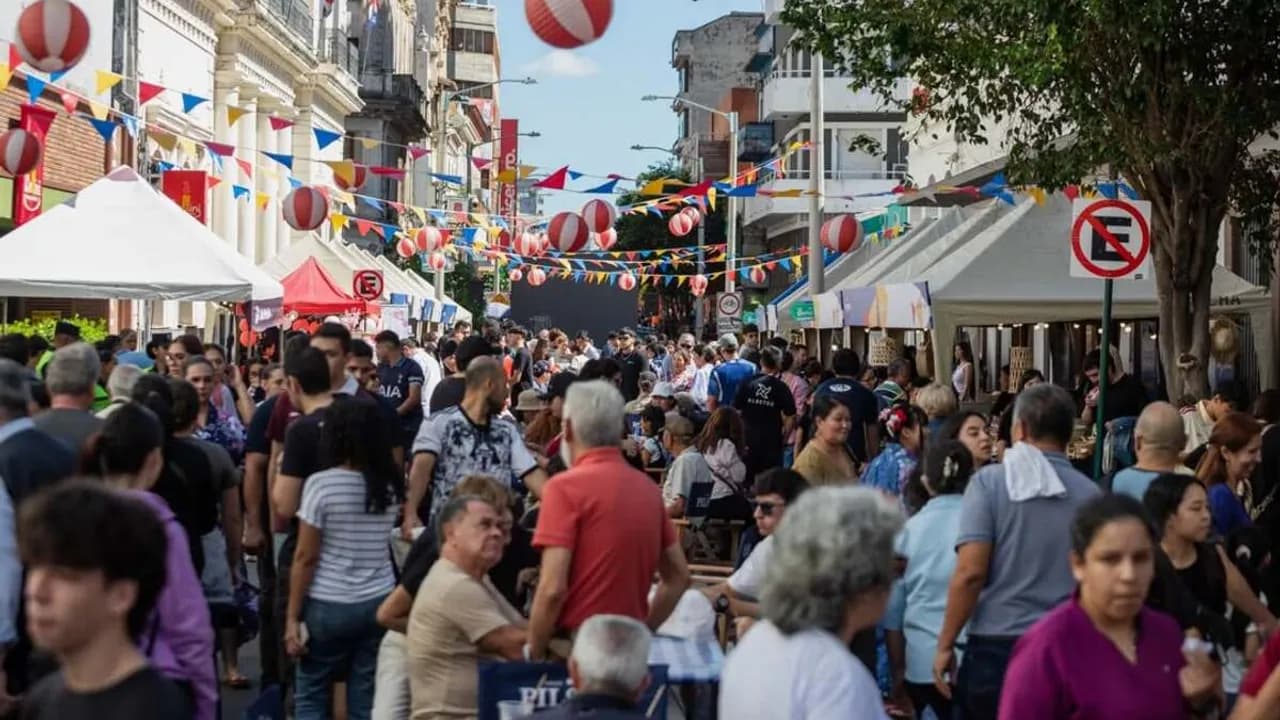 Multitud de personas recorren la calle Palma decorada con banderines festivos y puestos feriales bajo el sol.