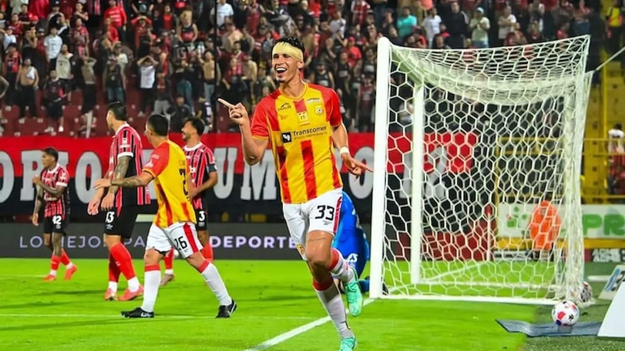 Futbolista con camiseta roja y amarilla y vendaje en la cabeza celebra un gol en el campo de juego.