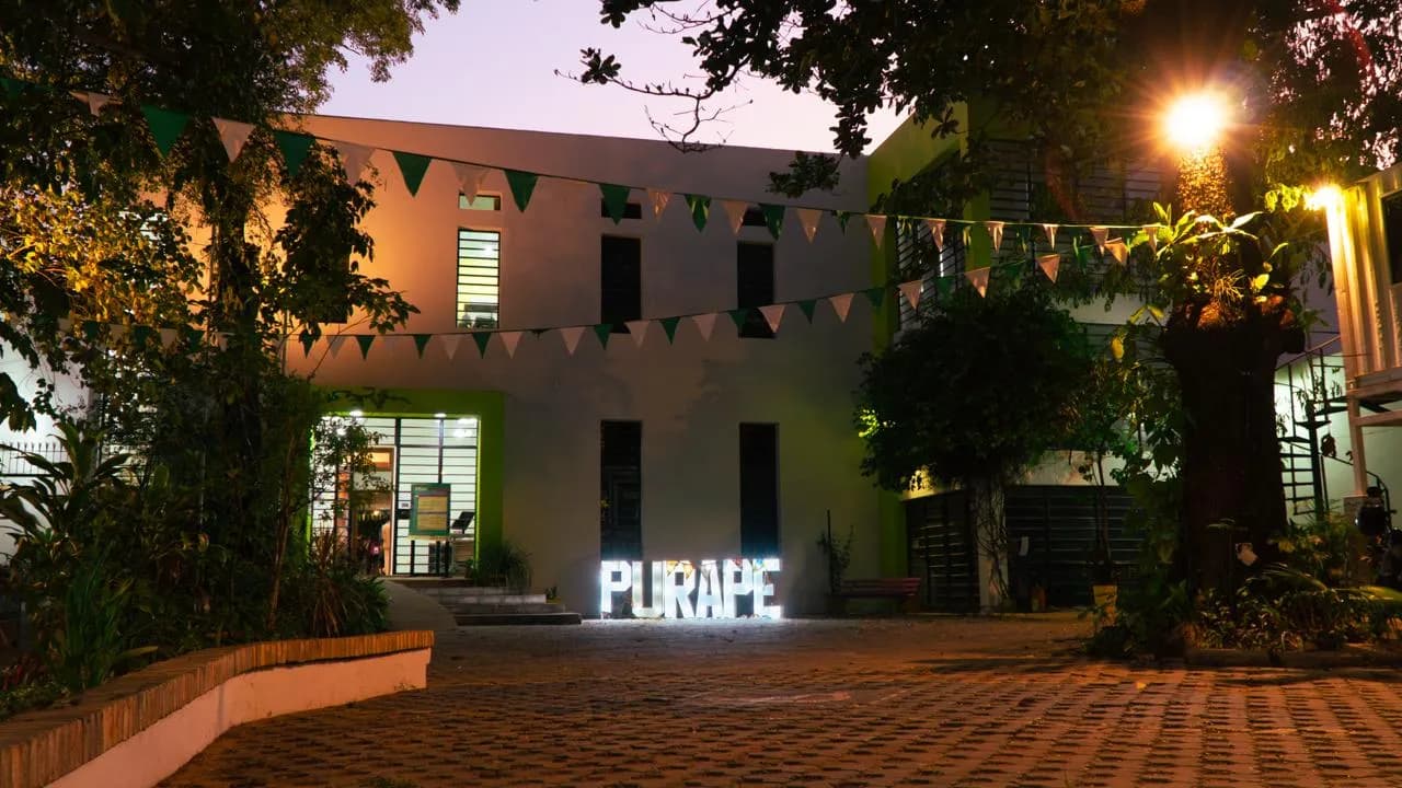 Letras luminosas que forman la palabra Purape en el patio nocturno del Instituto Cultural Paraguayo-Alemán
