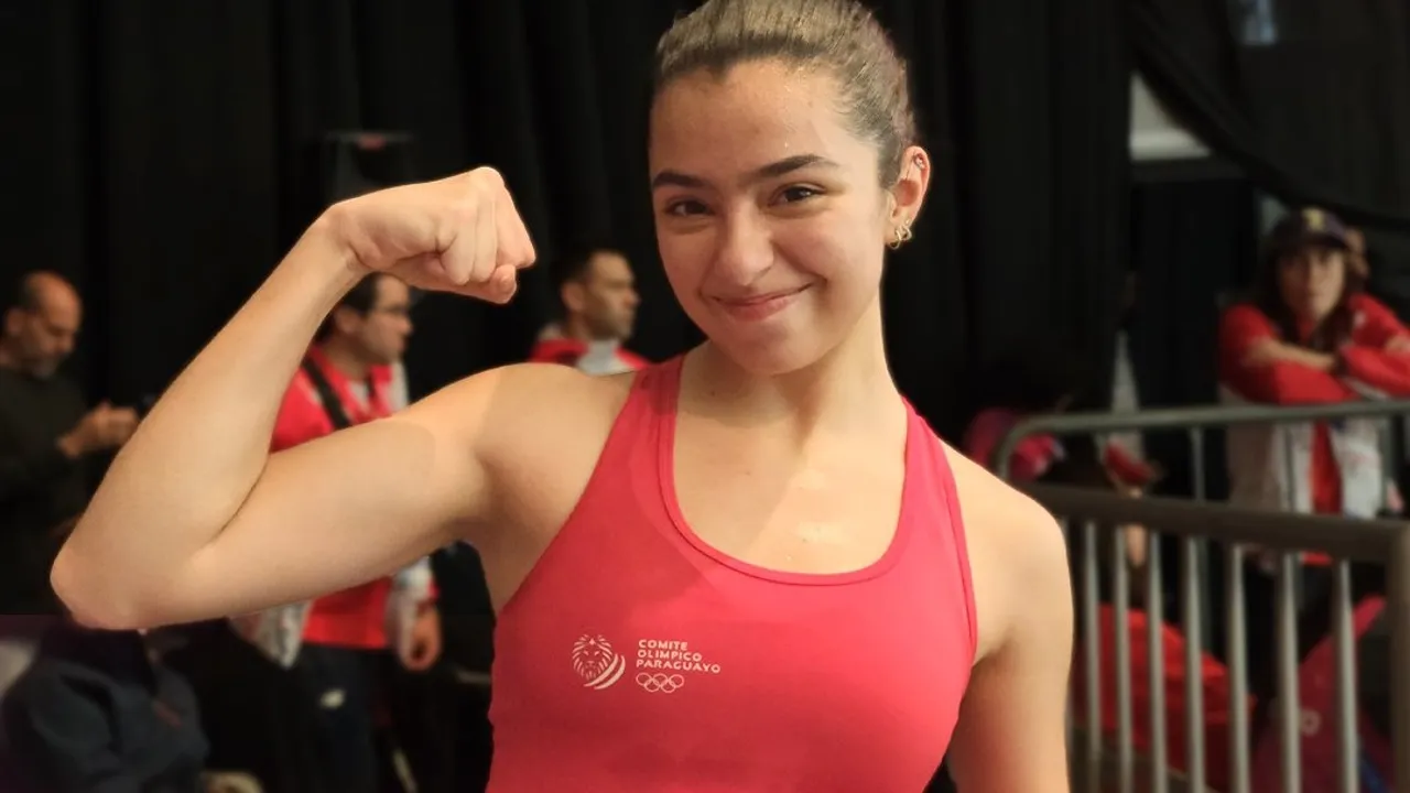 Joven atleta sonríe y muestra el músculo de su brazo vestida con una musculosa deportiva roja.