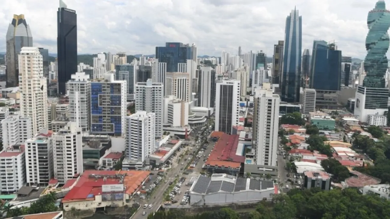 Panorámica de la Ciudad de Panamá con rascacielos modernos, avenidas comerciales y zonas verdes bajo cielo nublado.