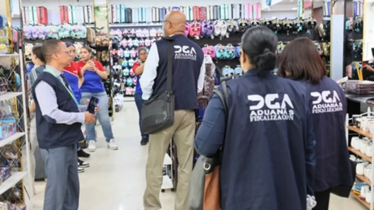 Inspectores con chalecos de fiscalización aduanera revisan el interior de un comercio con calzados y mercaderías.