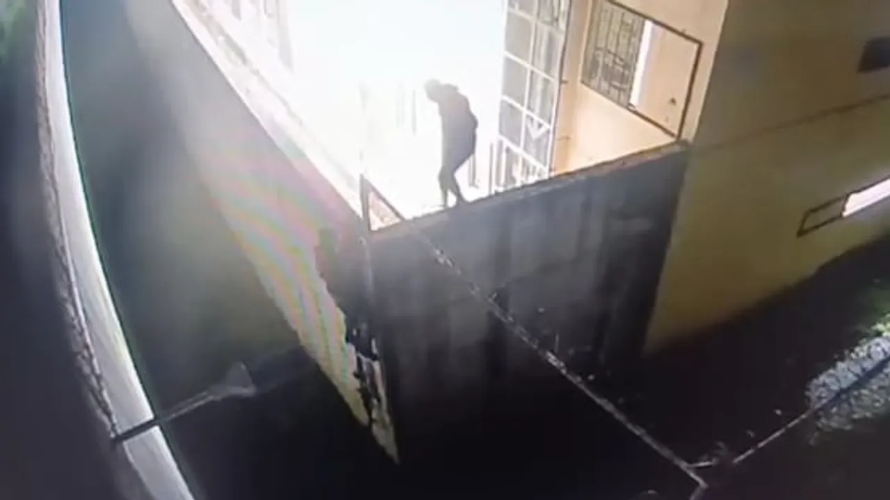 Captura de cámara de seguridad que muestra a una persona vestida de oscuro trepando la pared de un edificio penitenciario.