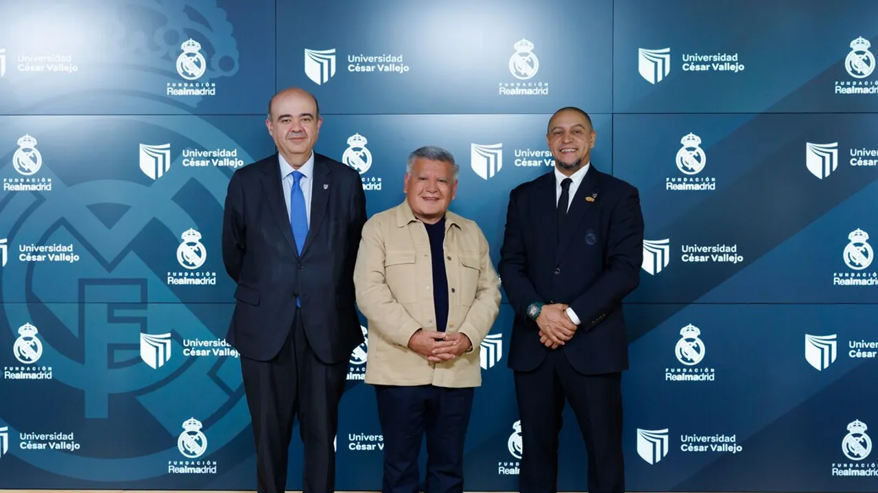 Tres hombres posan sonrientes de pie frente a un panel institucional azul con logotipos deportivos y universitarios.