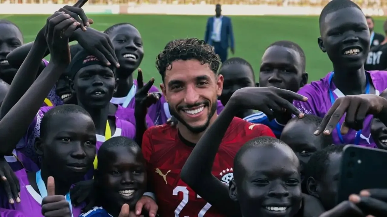 Omar Marmoush sonríe en el campo de juego rodeado de niños que celebran y se toman una fotografía junto a él.