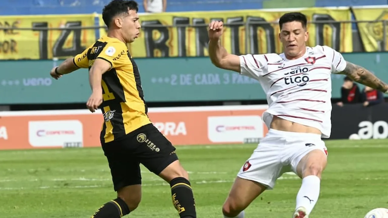 Dos futbolistas disputan el balón en el césped durante una jugada intensa en el estadio.