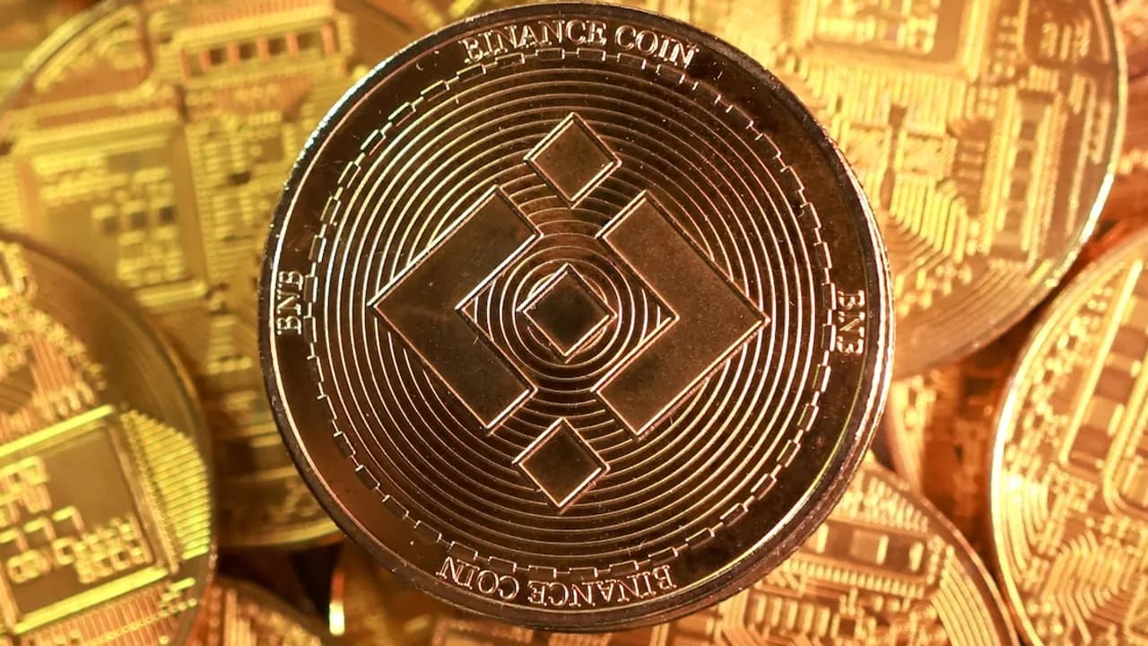 Moneda metálica dorada con el logotipo grabado de Binance Coin en primer plano sobre varias fichas similares