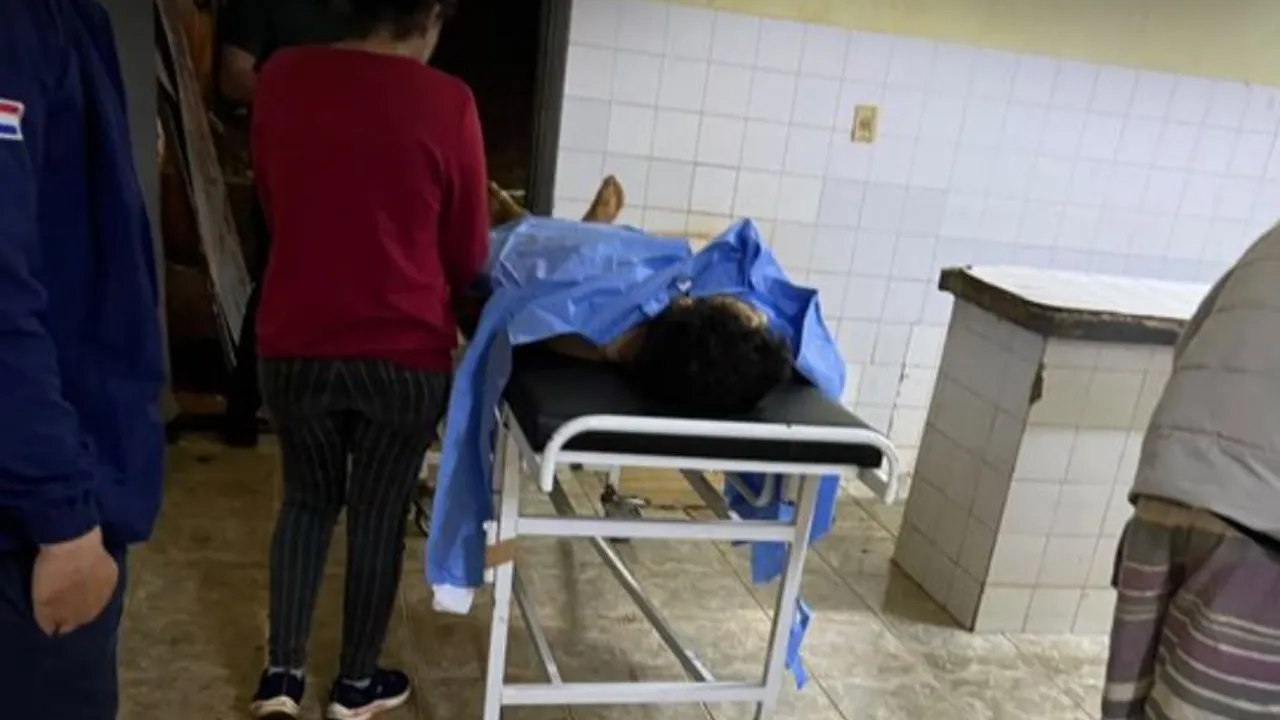 Hombre herido en una camilla hospitalaria cubierto con manta quirúrgica celeste en sala médica