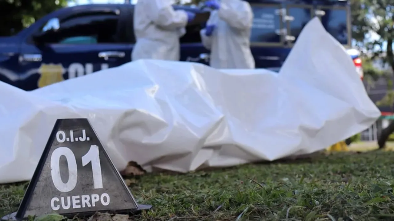 Cuerpo cubierto con una manta plástica blanca y marcador policial número uno en una escena del crimen.