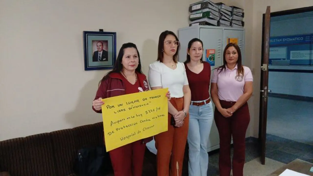 Cuatro mujeres exhiben un cartel amarillo que reclama un ámbito laboral libre de violencia dentro del recinto hospitalario.