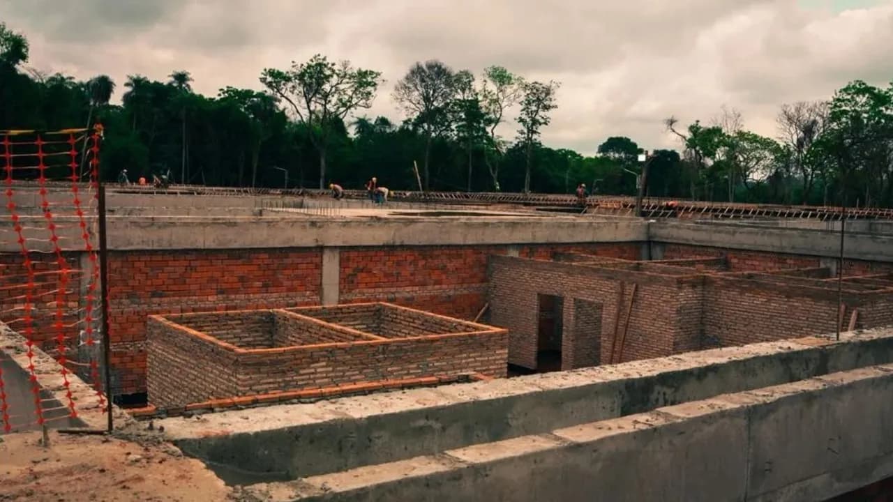 Estructura de hormigón y muros de ladrillo en construcción de un hospital público bajo cielo nublado