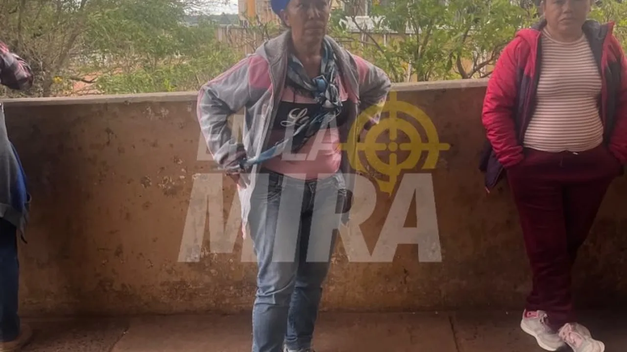 Mujeres paradas en una galería al aire libre mientras observan hacia un costado durante un procedimiento policial.
