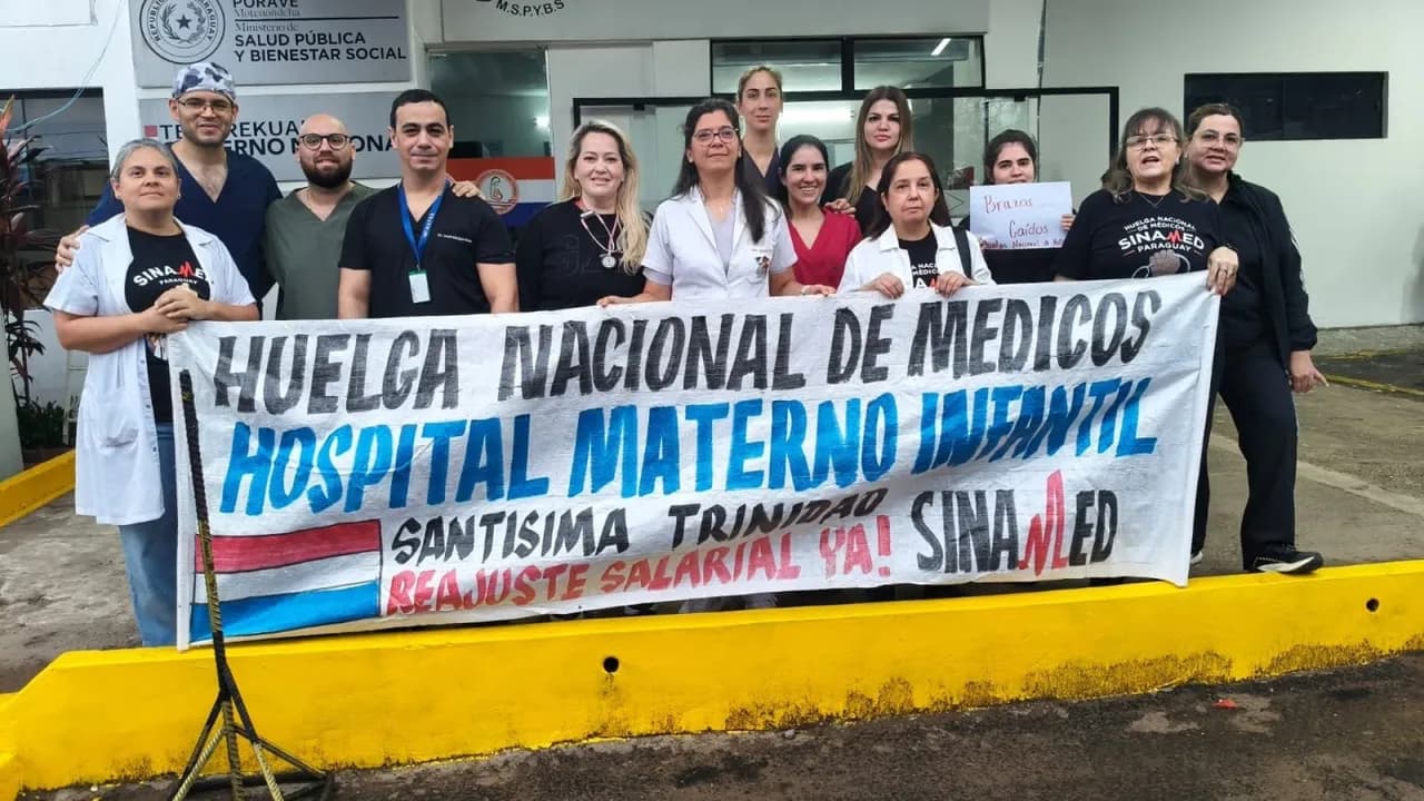 Personal de blanco sostiene una pancarta de Sinamed frente a un centro asistencial en reclamo de reajuste salarial.