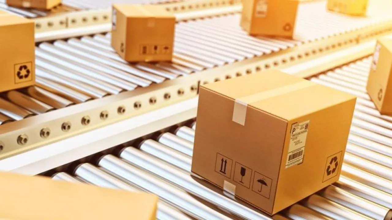 Cajas de cartón selladas y etiquetadas avanzan sobre una cinta transportadora de rodillos metálicos.