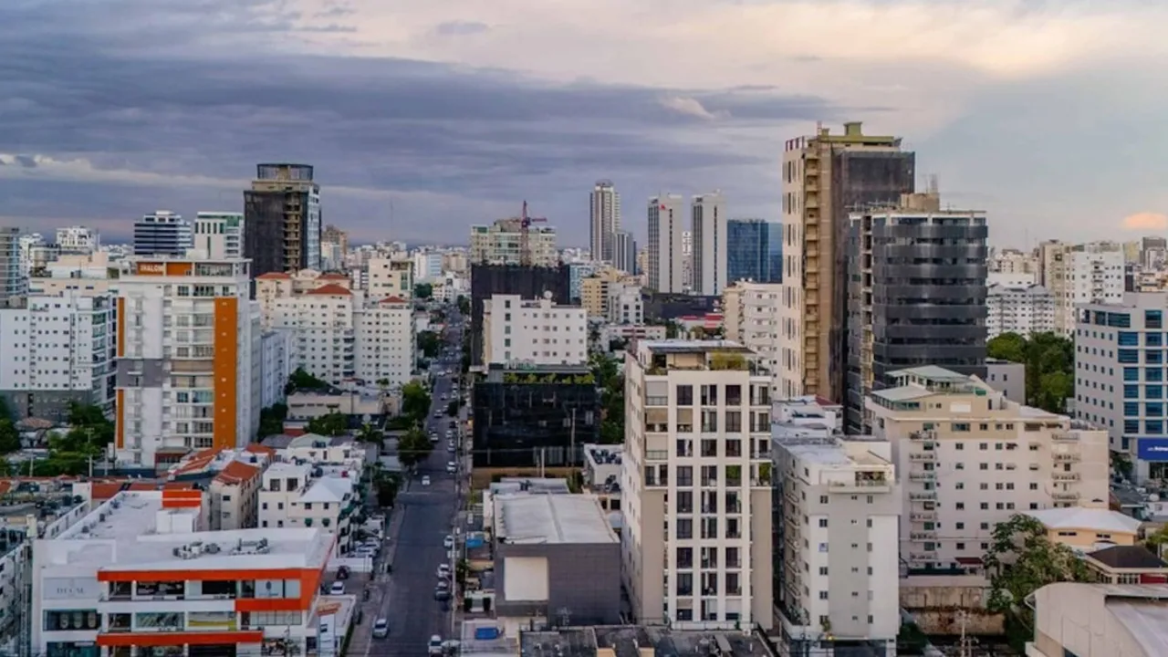 Vista aérea de edificios residenciales y corporativos en una avenida urbana bajo cielo nublado.