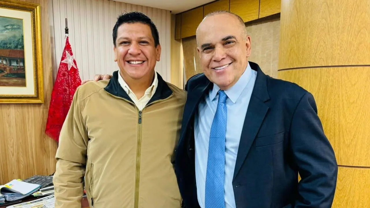 Claudio Samaniego y el senador Basilio Núñez sonríen de pie dentro de un despacho oficial con bandera paraguaya.