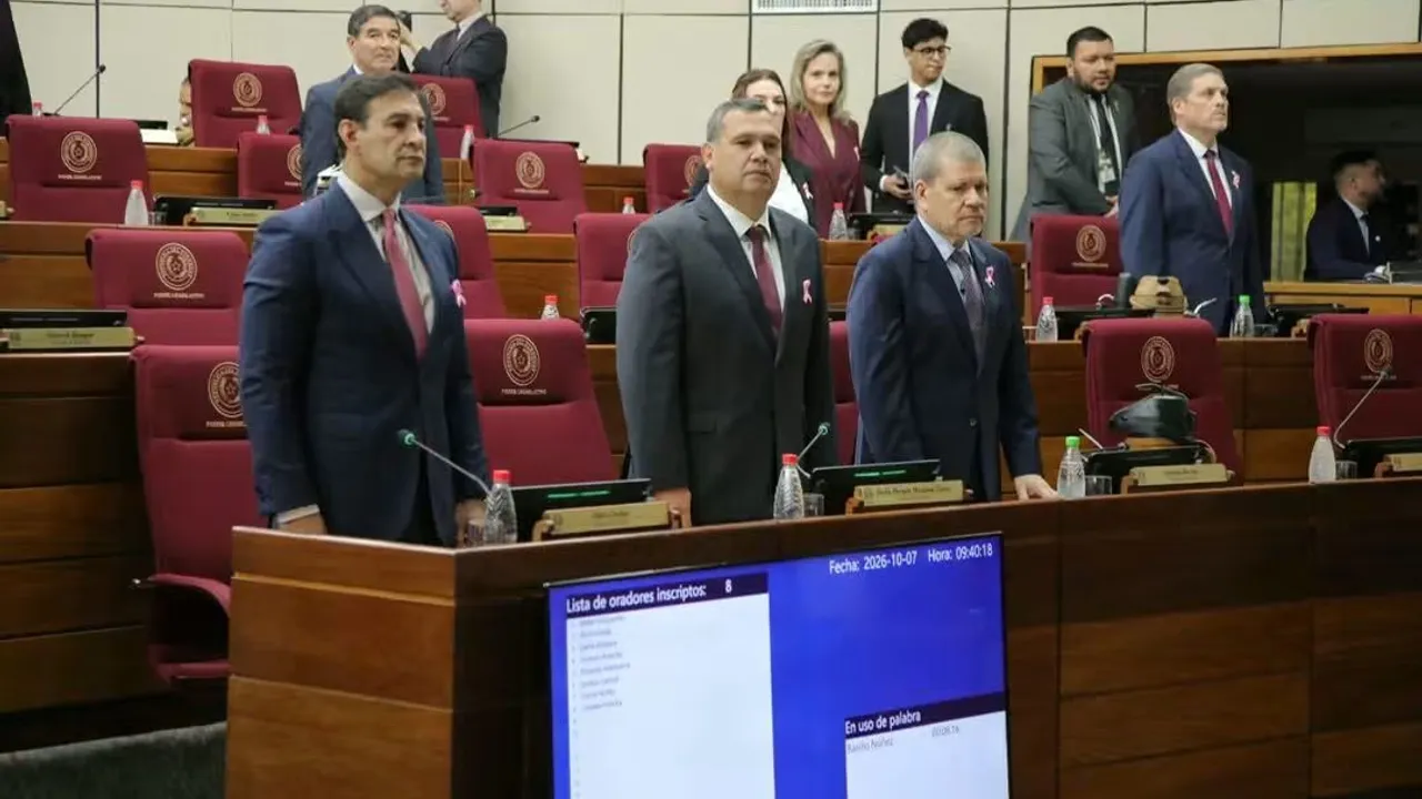 Tres legisladores con traje formal permanecen de pie en la mesa directiva de la sala de sesiones del Congreso