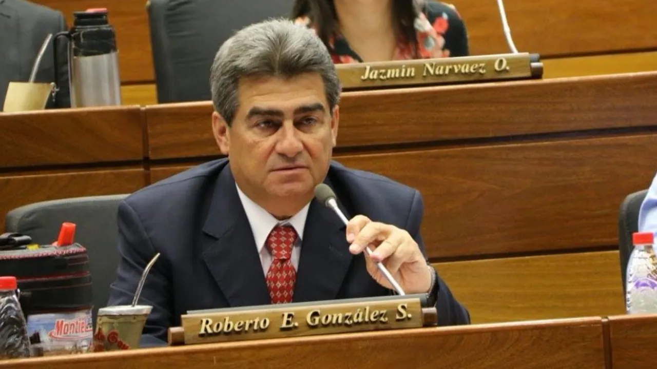 Roberto González con traje oscuro y corbata roja habla ante el micrófono en su banca de la Cámara de Diputados.
