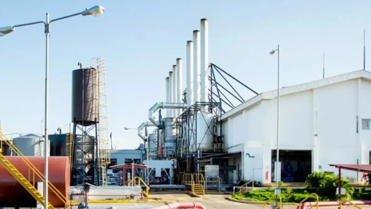 Instalaciones industriales de una central termoeléctrica con chimeneas metálicas blancas y tanques de combustible.
