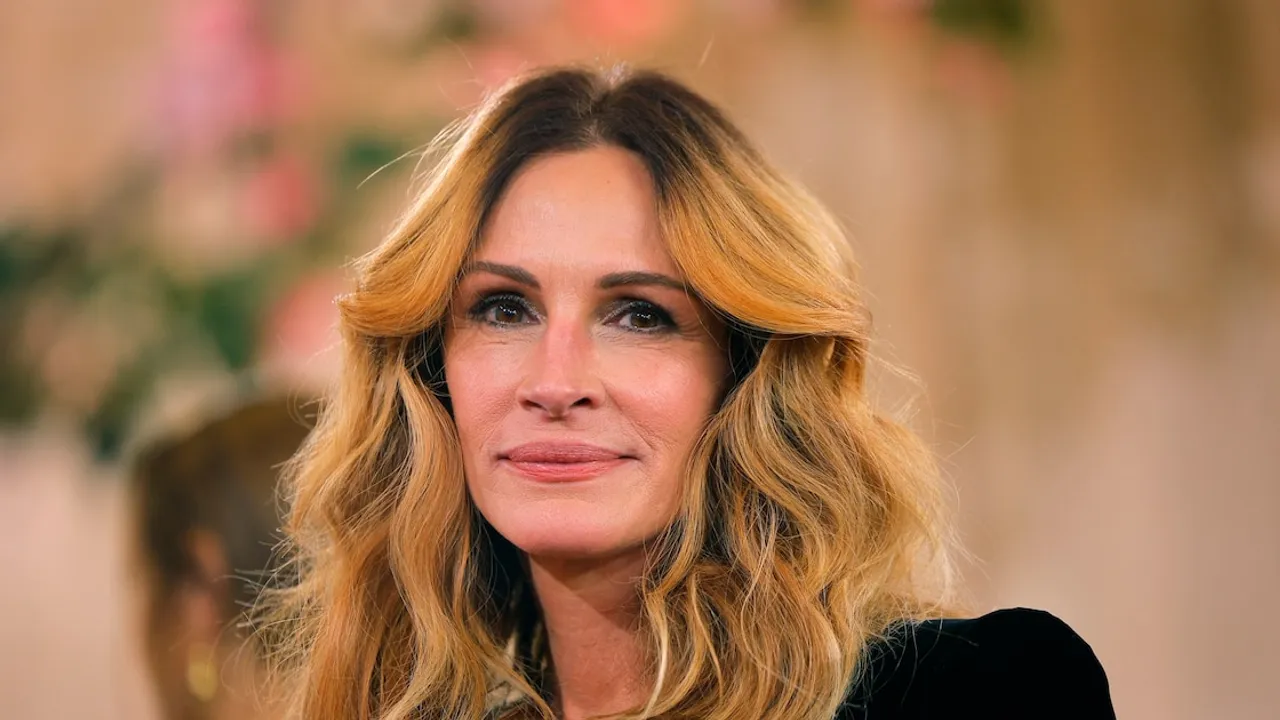 Primer plano de la actriz Julia Roberts sonriendo con su cabello rubio ondulado en un evento público