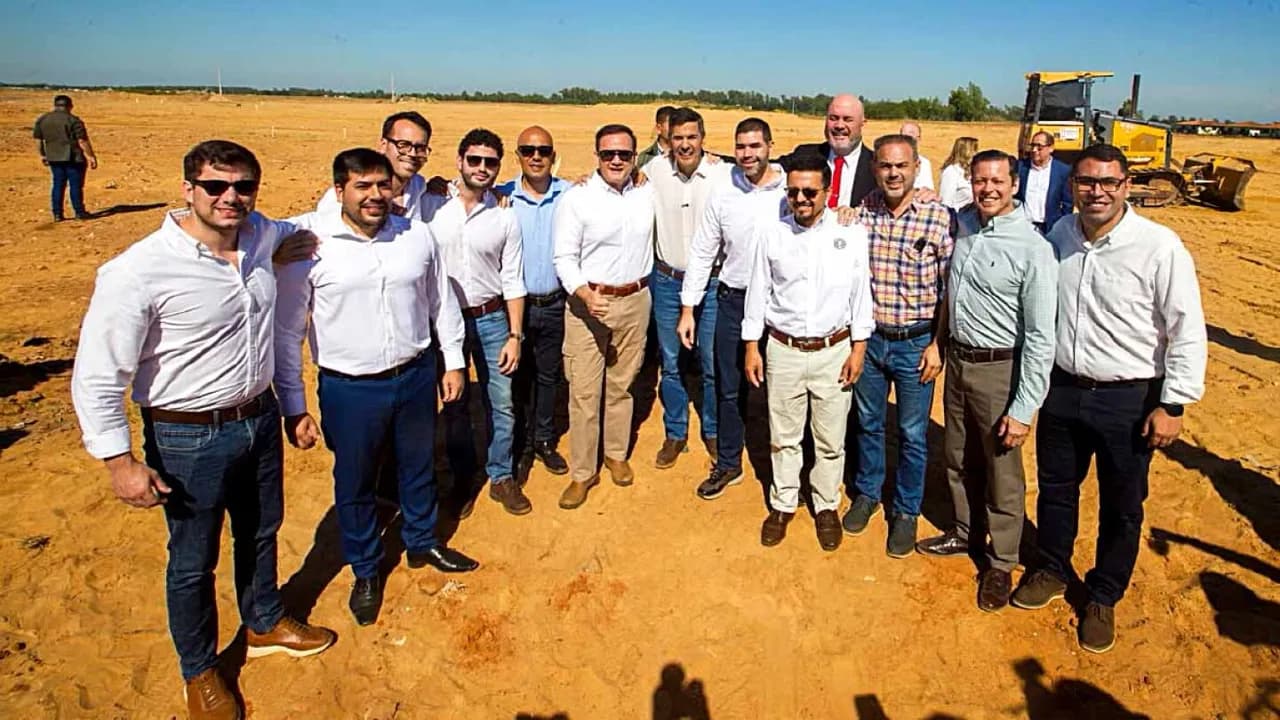 Santiago Peña y dirigentes posan en un terreno de obras viales al aire libre con maquinaria pesada detrás.