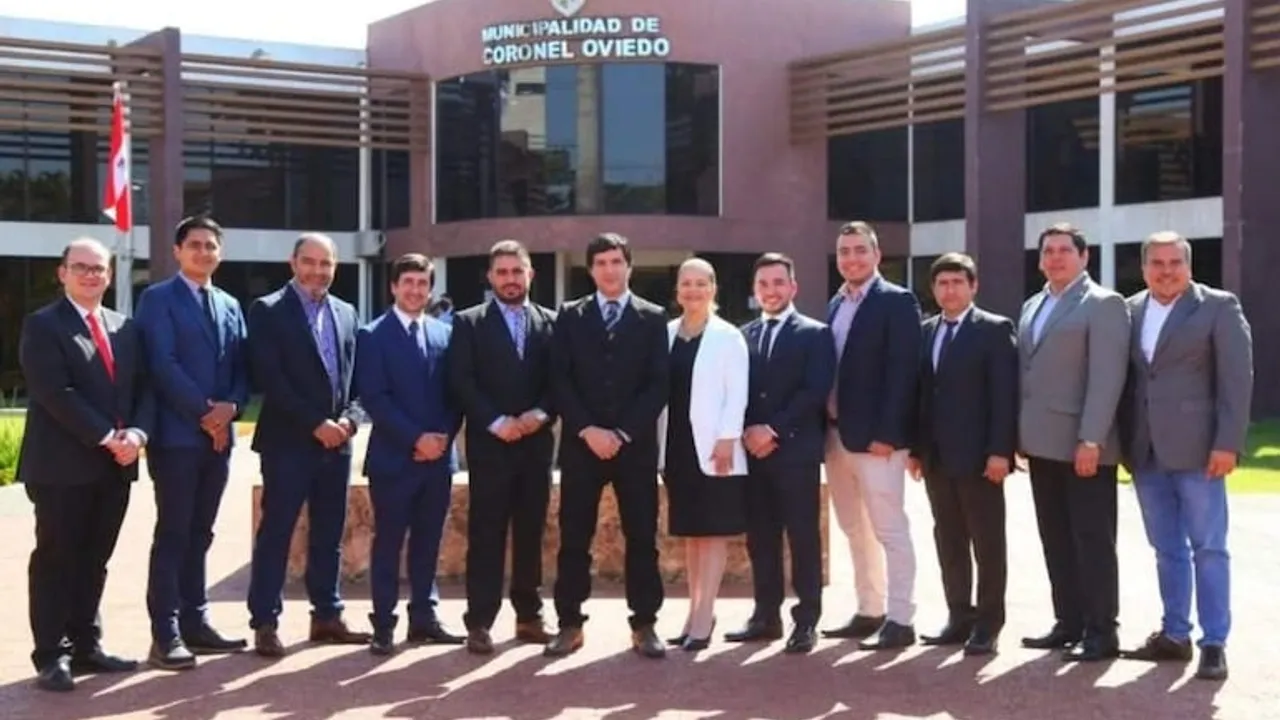 Grupo de autoridades y concejales en fila frente a la fachada del edificio de la Municipalidad de Coronel Oviedo.