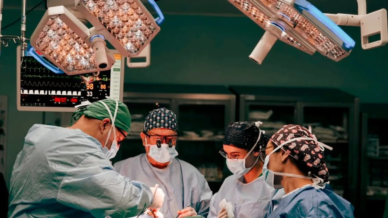 Cuatro profesionales de la salud con mascarillas y gorros realizan una operación bajo luces de quirófano.