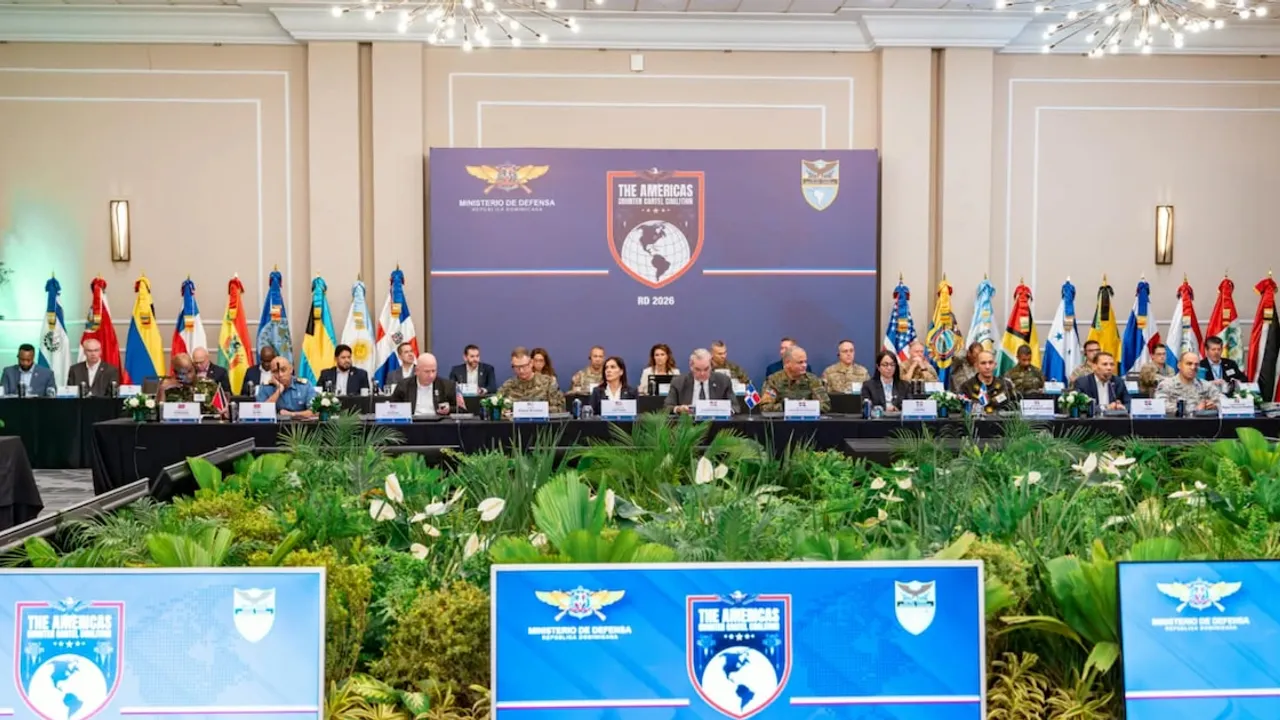 Delegados de seguridad de 19 países sentados en una mesa de conferencia con banderas americanas detrás.