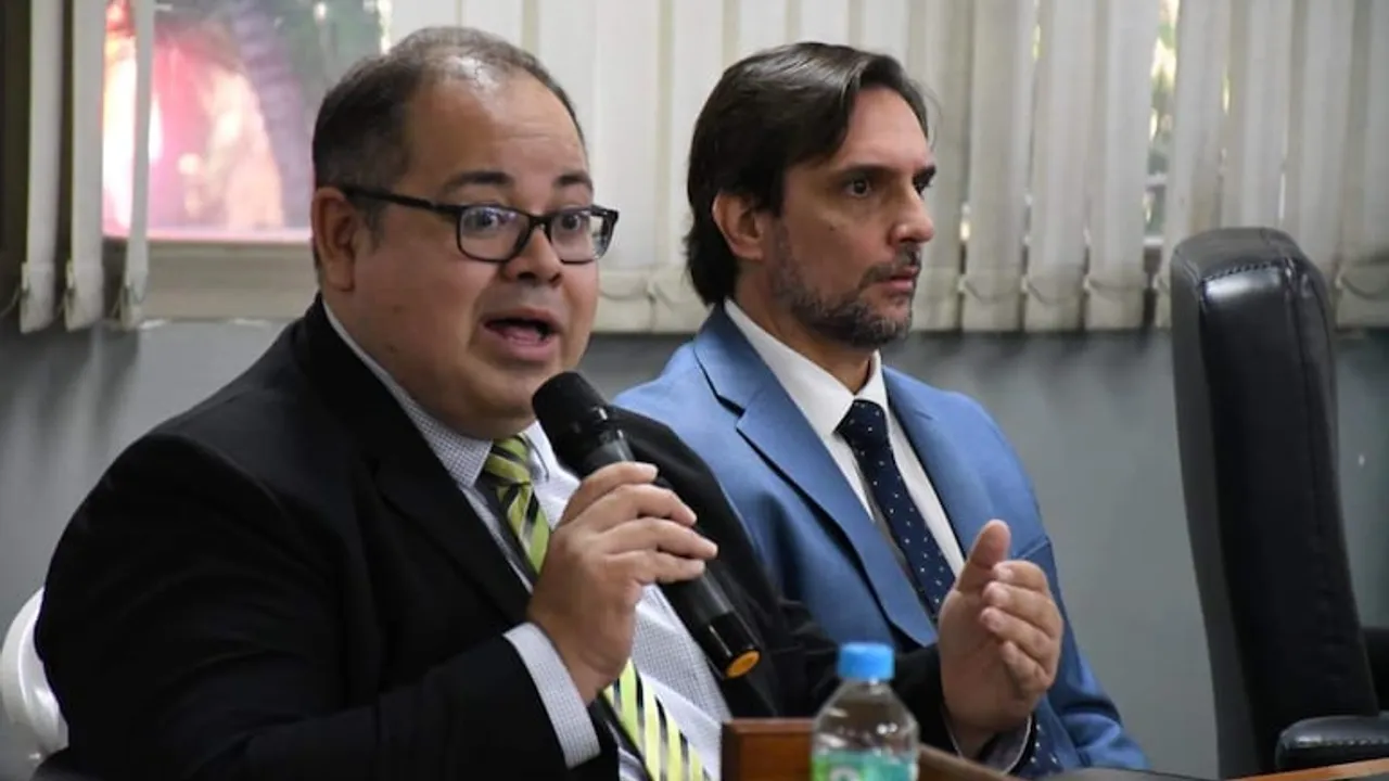 Dos autoridades municipales de Asunción comparecen con micrófono en mano durante una exposición ante la Junta Municipal.