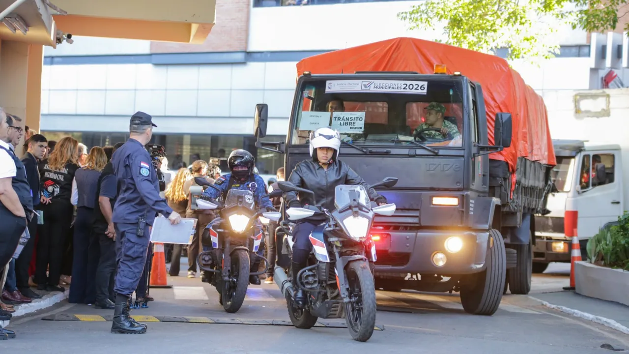 Un camión de carga escoltado por agentes policiales en motocicleta sale durante el operativo de traslado electoral.