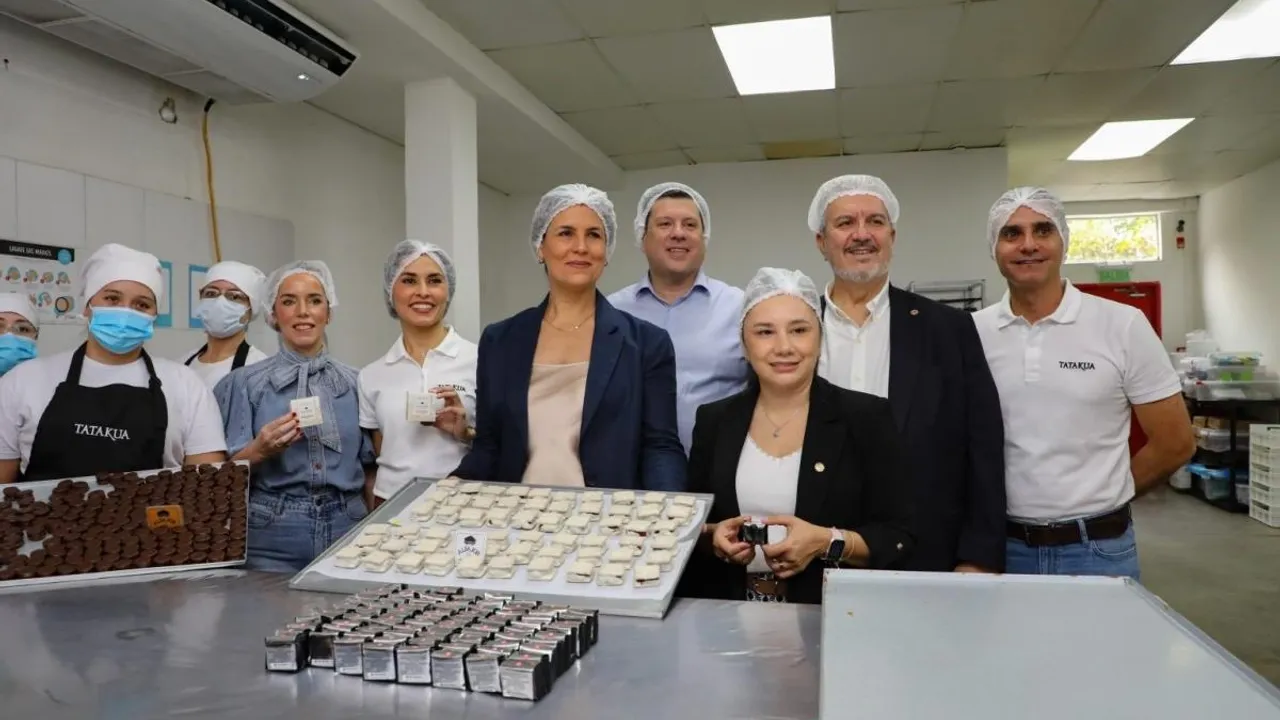 Autoridades y trabajadoras con cofias posan frente a una mesa con alfajores artesanales empaquetados.