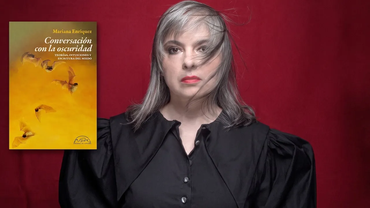 Retrato de Mariana Enriquez vestida de negro con su libro Conversación con la oscuridad al costado.